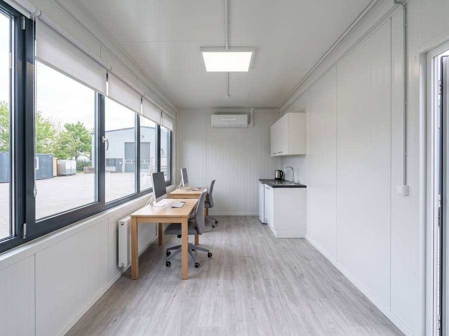 Fertig ausgebauter Bürocontainer innen mit Schreibtischen, Klimagerät und Kleinküche