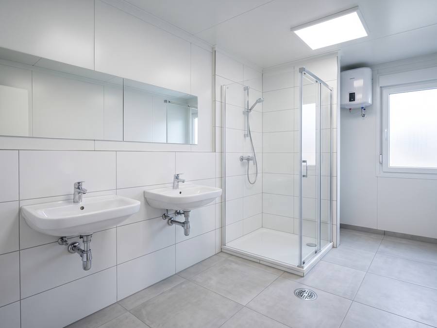 Innenansicht eines neuen Sanitärcontainers mit zwei Waschbecken und Duschkabine